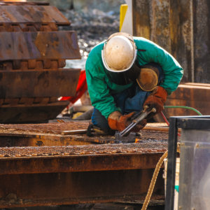 Trabajador de construcción enfocado en la soldadura, resaltando la necesidad de proteger los Derechos en incapacidad permanente en trabajos de riesgo.