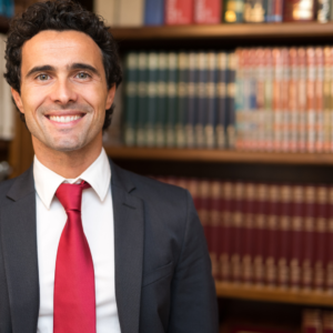 Retrato de abogado sonriente en biblioteca legal, representando asesoría en casos de despido sin indemnización